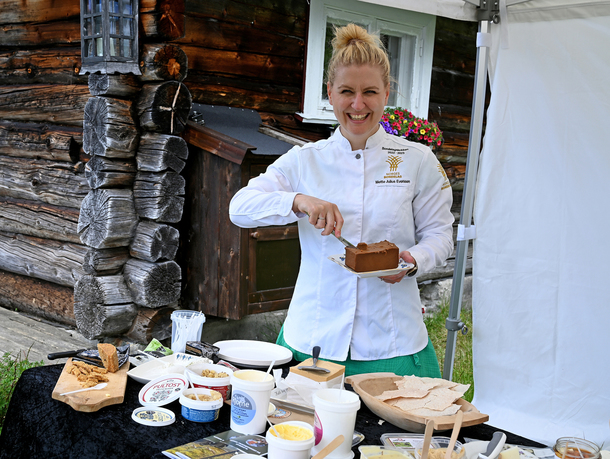 Bondelagskokk Mette Julius Evensen smiler bak en bord fullt av deilig ost. I hånden holder hun en tallerken med brunost.