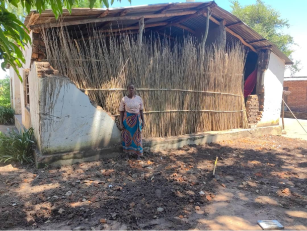 Bonde i Malawi foran huset sitt som mangler en vegg