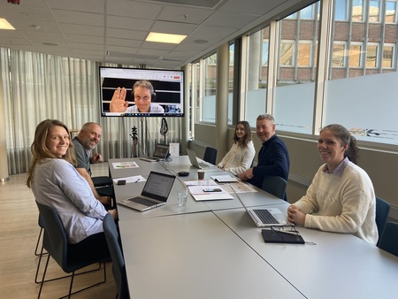 Ansatte ved Norges Bondelag sitter langs et bord i et møterom med videosamtale på storskjerm.