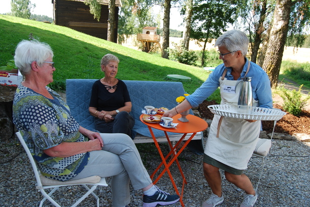 Her får Kari Hveem og Marit Børresen servert vaffel med bringebær av mor og sesonghjelp Anne Heiberg